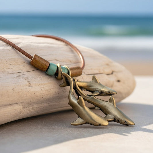 Big Blue by Roland St John bronze necklace with three grey reef sharks pendant on braided cord with turquoise beads.