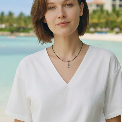 Big Blue by Roland St John sterling silver hammerhead shark choker necklace on a black cable wire worn by a woman on a beach.