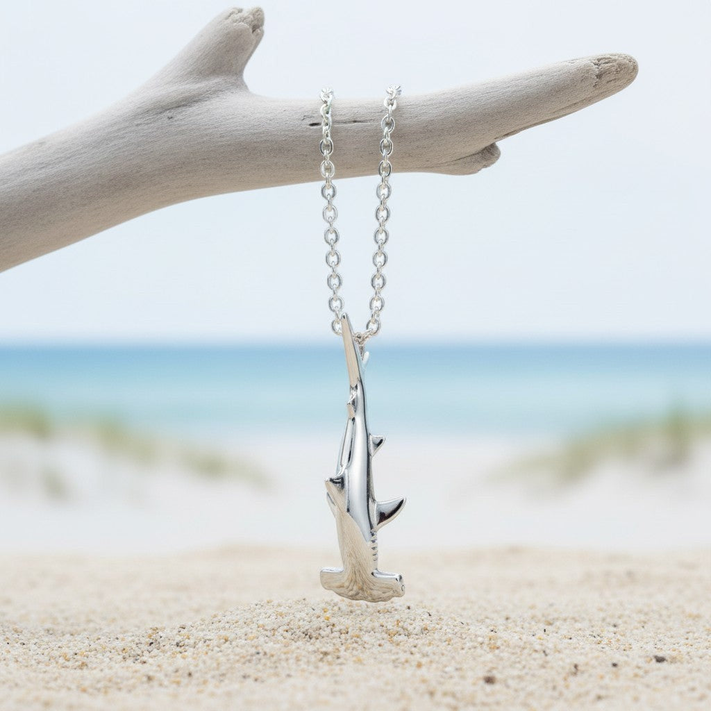 Big Blue by Roland St John sterling silver mini hammerhead shark pendant necklace on a beach background.