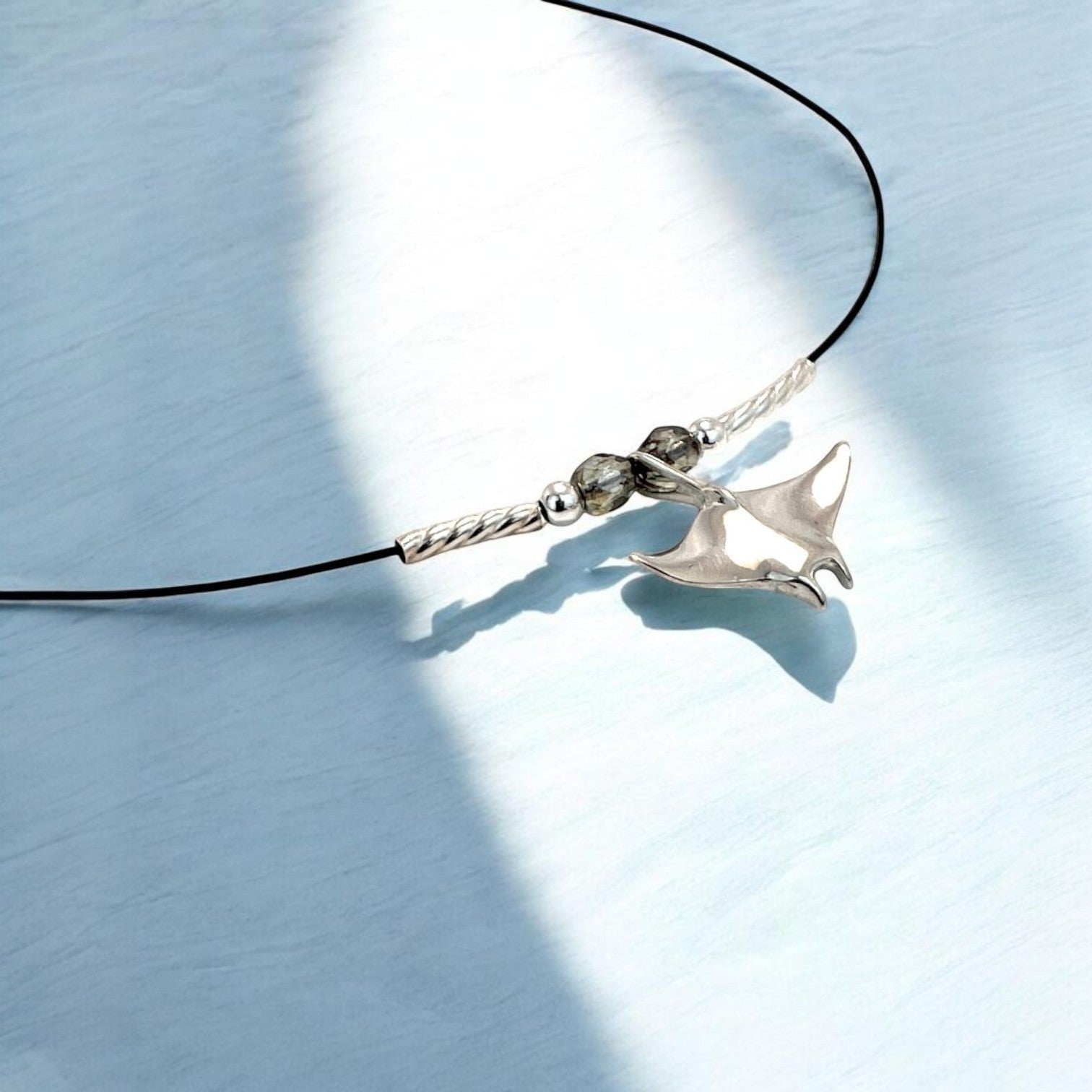 Big Blue by Roland St John sterling silver miniature manta ray choker necklace with grey beads on black cord.