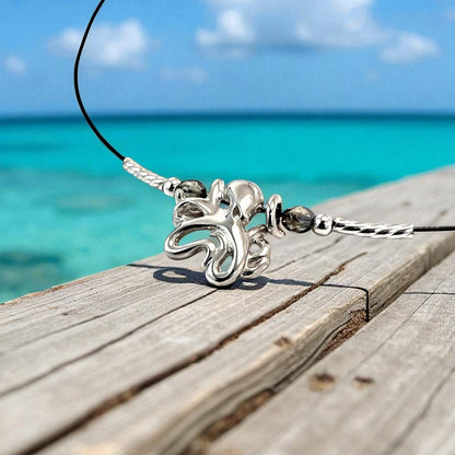 Big Blue by Roland St John sterling silver choker necklace with a mini octopus pendant and grey beads, set against a tropical ocean backdrop.