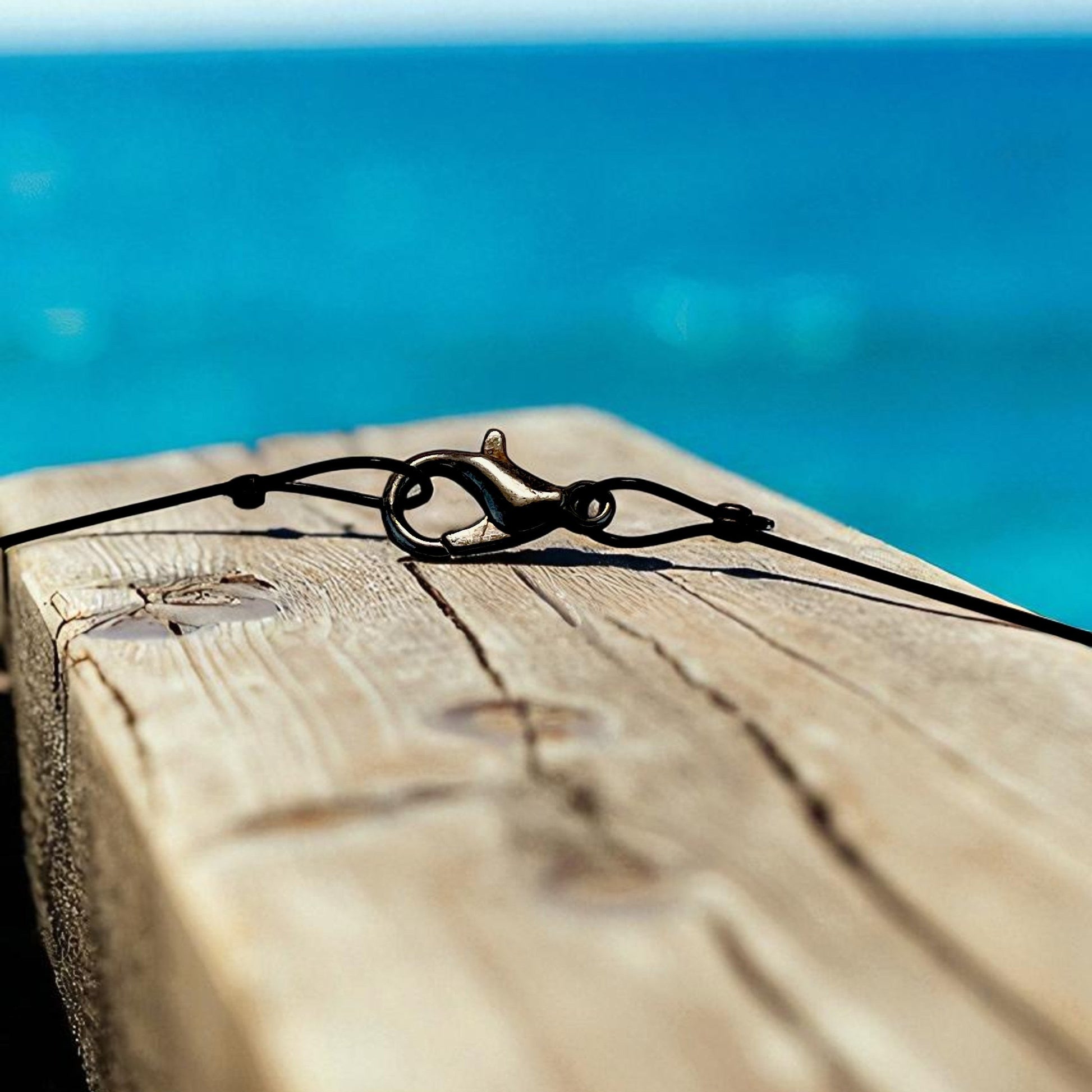 Big Blue by Roland St John sterling silver choker necklace with octopus pendant clasp detail against a wooden surface and blue ocean background.
