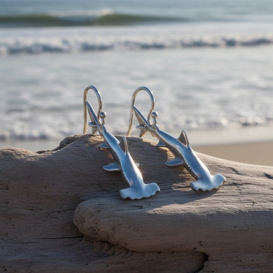 Big Blue by Roland St John sterling silver hammerhead shark earrings on driftwood with ocean background.