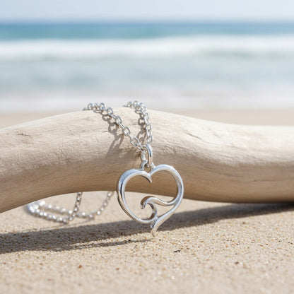 Big Blue by Roland St John sterling silver heart necklace with wave detail, on a beach setting.