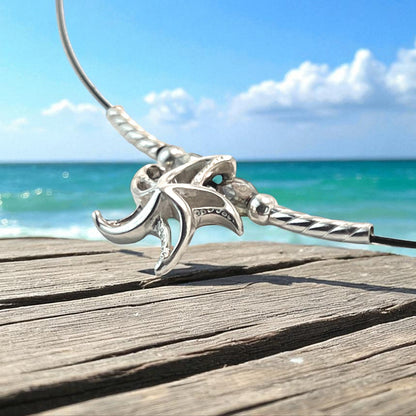 Big Blue by Roland St John sterling silver choker necklace with a detailed 3D starfish pendant, set against a beach and ocean backdrop.