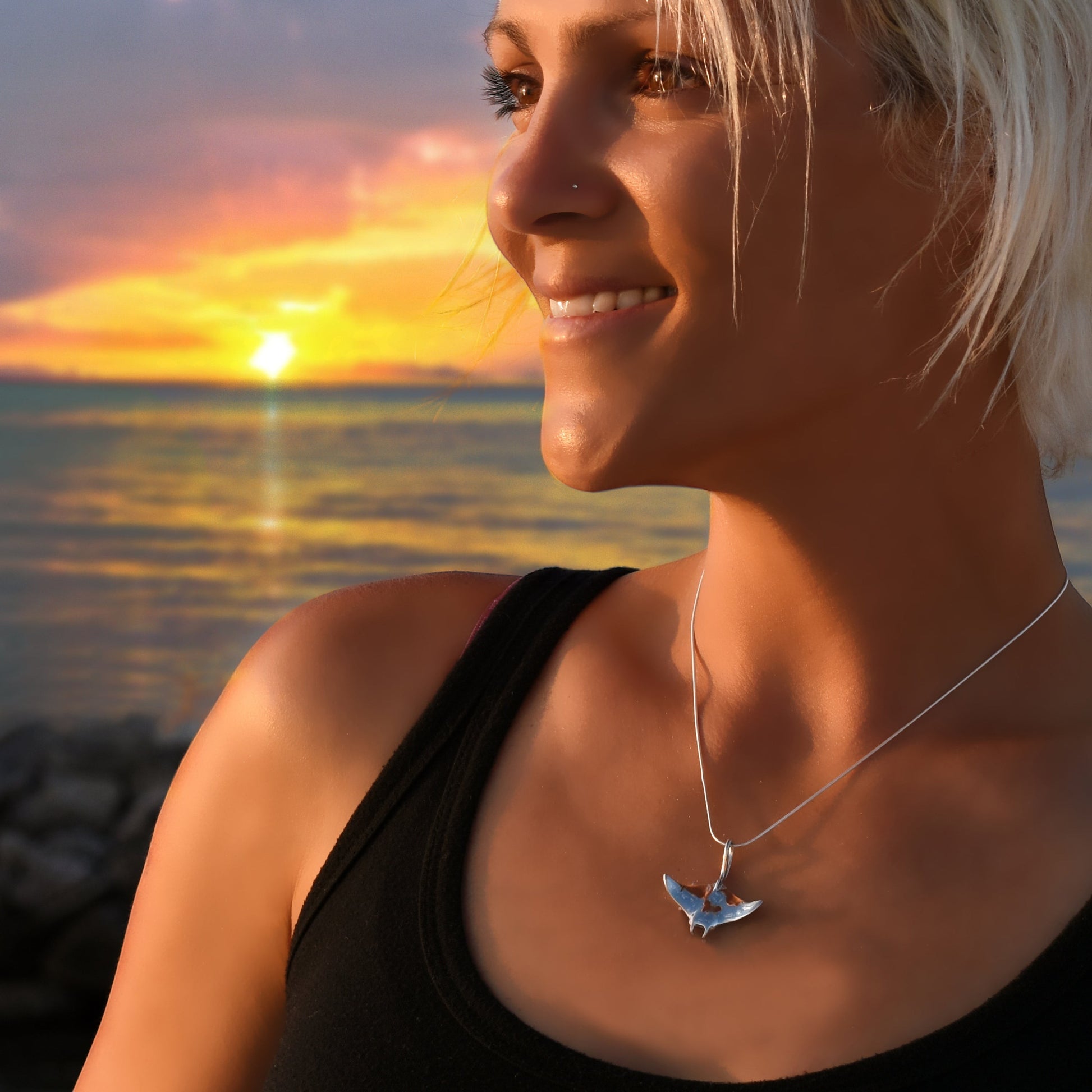 Big Blue by Roland St John sterling silver manta ray necklace on a woman at sunset by the ocean.
