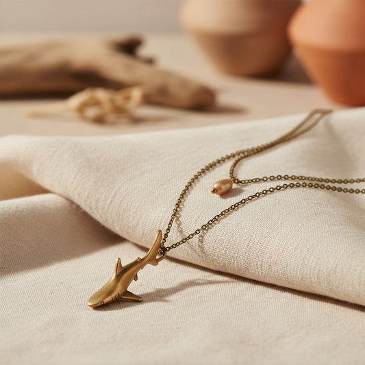 Big Blue by Roland St John bronze shark pendant necklace with layered chains and a peach bead. Coastal bohemian style.