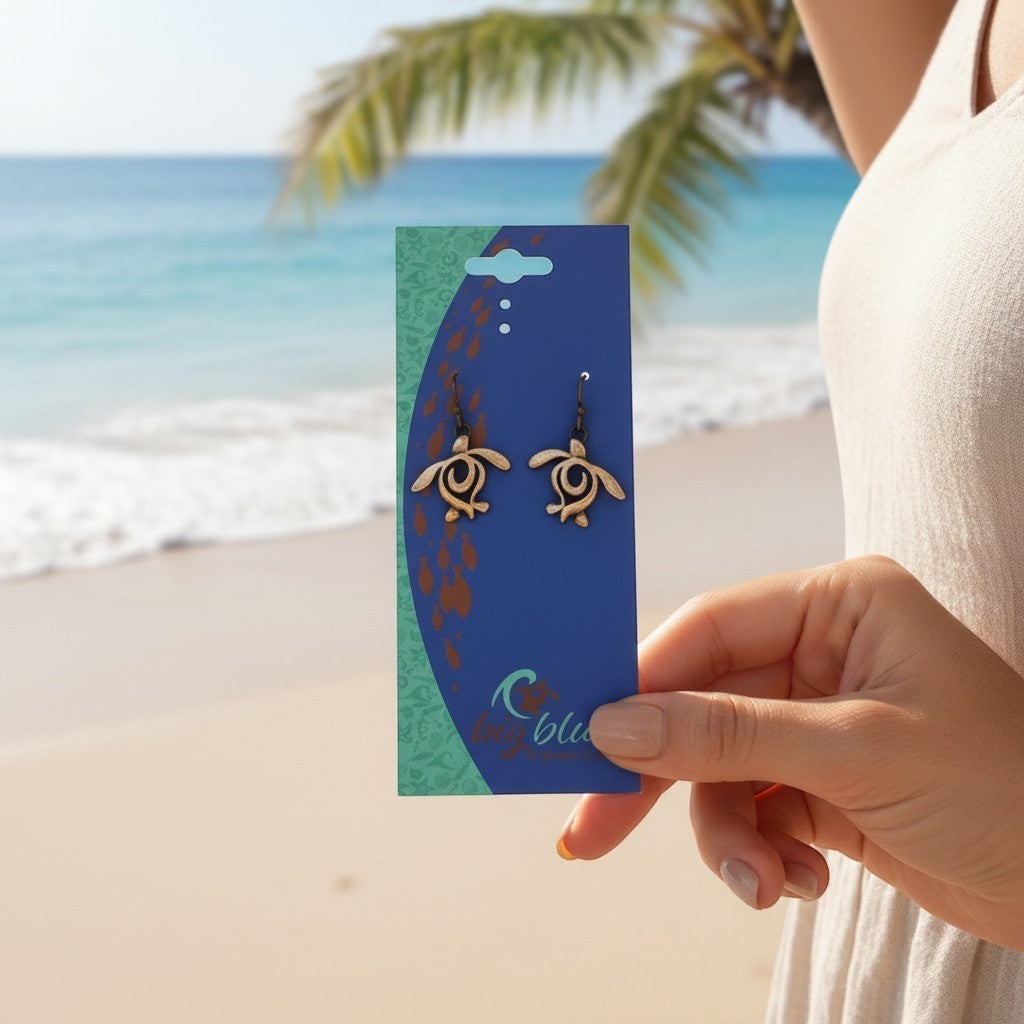 Big Blue by Roland St John bronze turtle drop earrings on card, beach background.