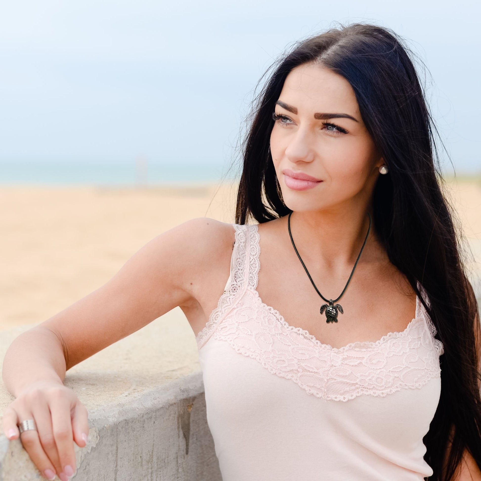 Big Blue by Roland St John sea turtle pendant in jet black finish on a black cord, worn by a woman at the beach.