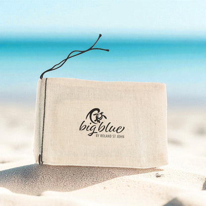 Big Blue by Roland St John sea turtle pendant in jet black finish, presented in a canvas pouch on a beach.