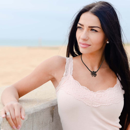 Big Blue by Roland St John Leggs octopus pendant necklace in jet black finish on a black cord worn by a woman on a beach.