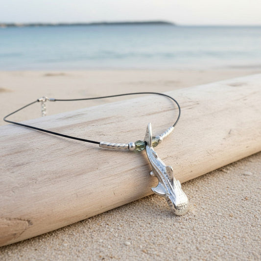 Big Blue by Roland St John sterling silver whale shark pendant choker with green beads on black cable wire, on a beach.