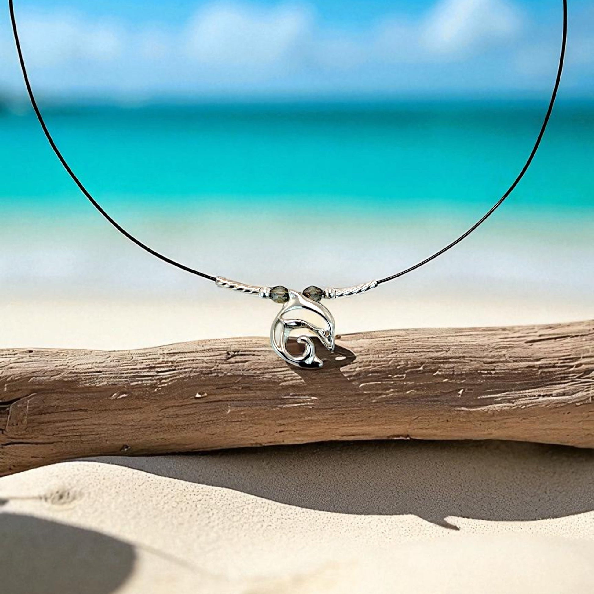 Big Blue by Roland St John sterling silver choker necklace with a miniature dolphin pendant, set on a black cord with two small grey beads.