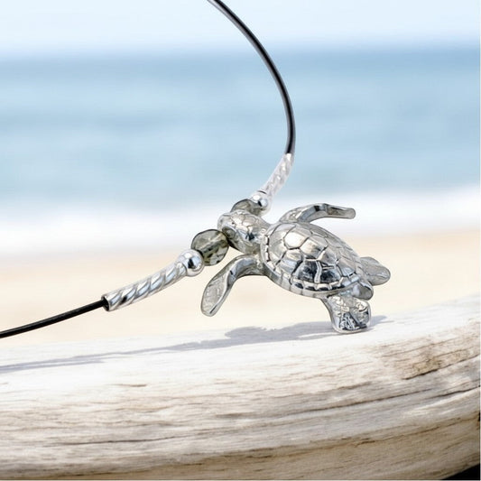 Big Blue by Roland St John sterling silver sea turtle choker necklace on cable wire with beaded accents, set against a beach background.