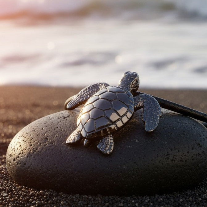 Big Blue by Roland St John realistic sea turtle pendant in jet black finish on a dark stone at the beach.