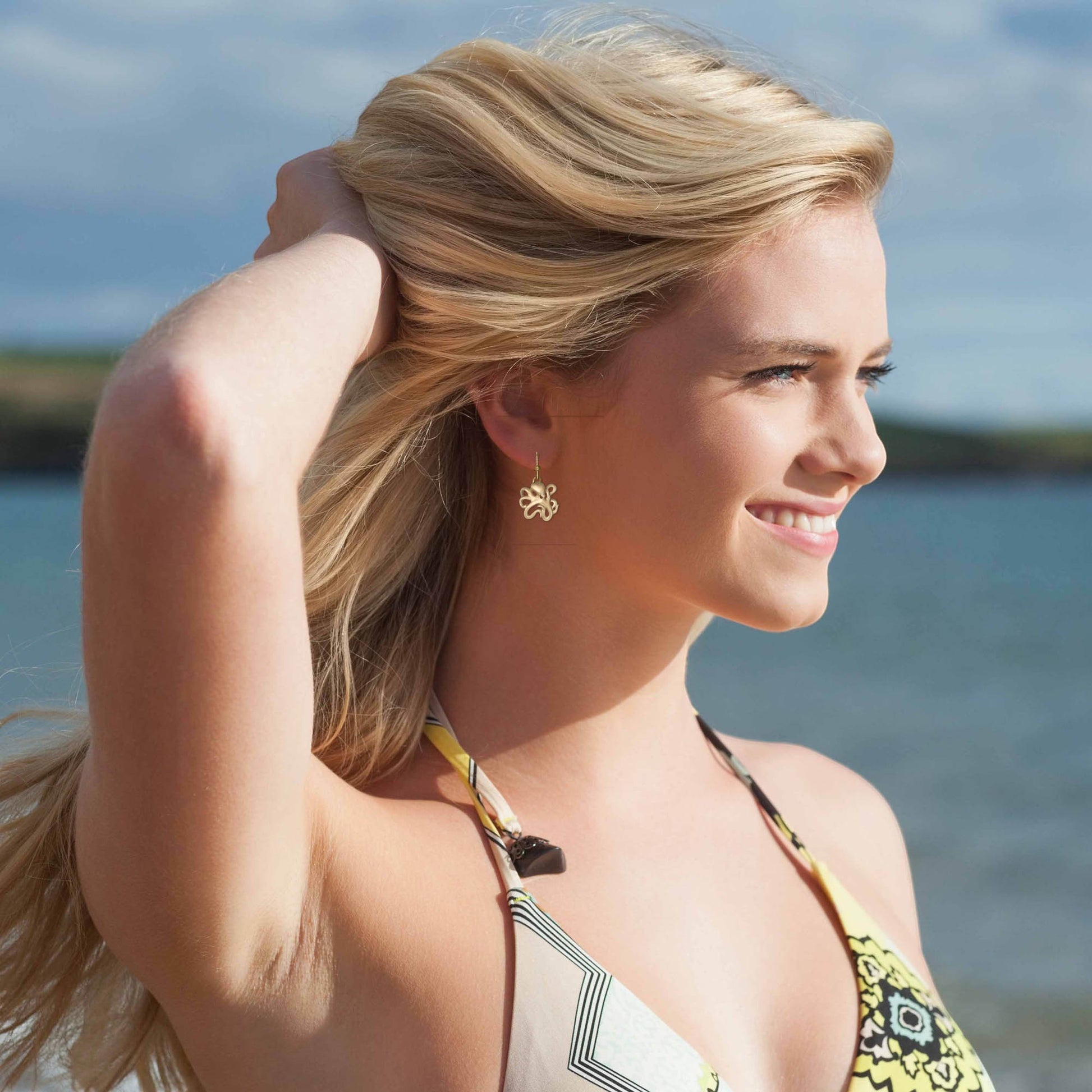 Big Blue by Roland St John bronze octopus drop earrings with secure ear wires, worn by a blonde model at the beach.