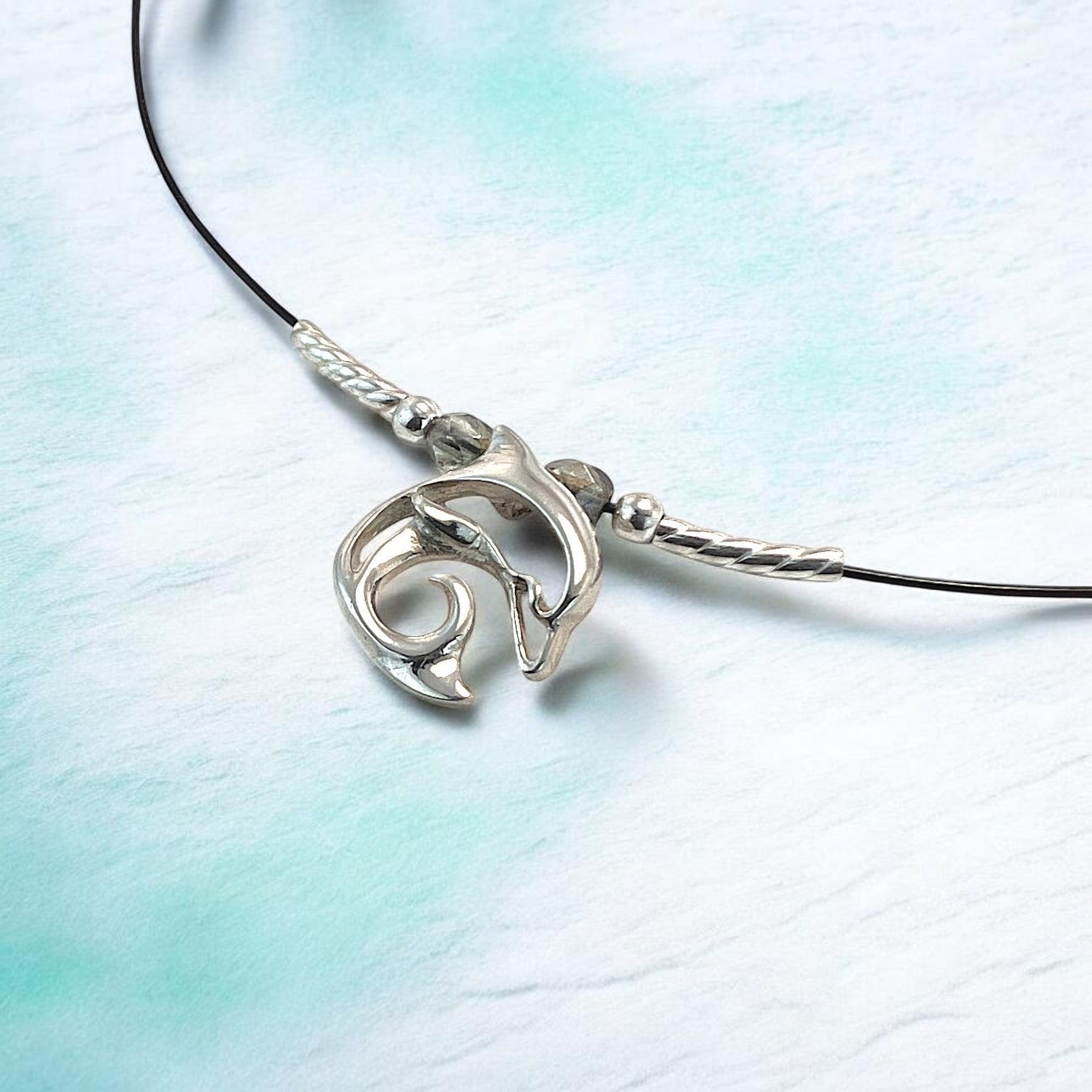Big Blue by Roland St John sterling silver choker necklace with a miniature dolphin pendant. Black cord with silver accents.