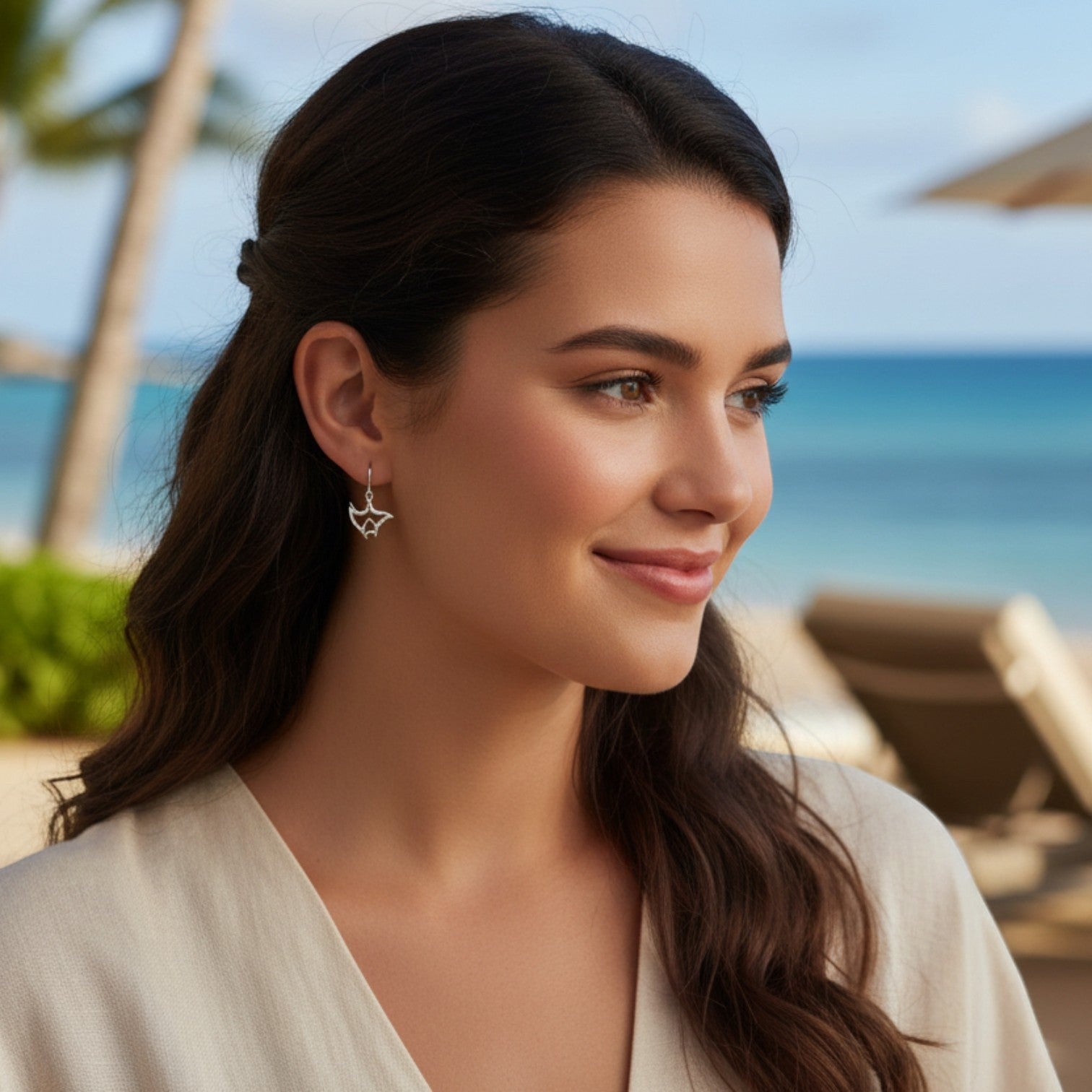 Big Blue by Roland St John "Big Ray" sterling silver manta ray drop earrings on a model at the beach.