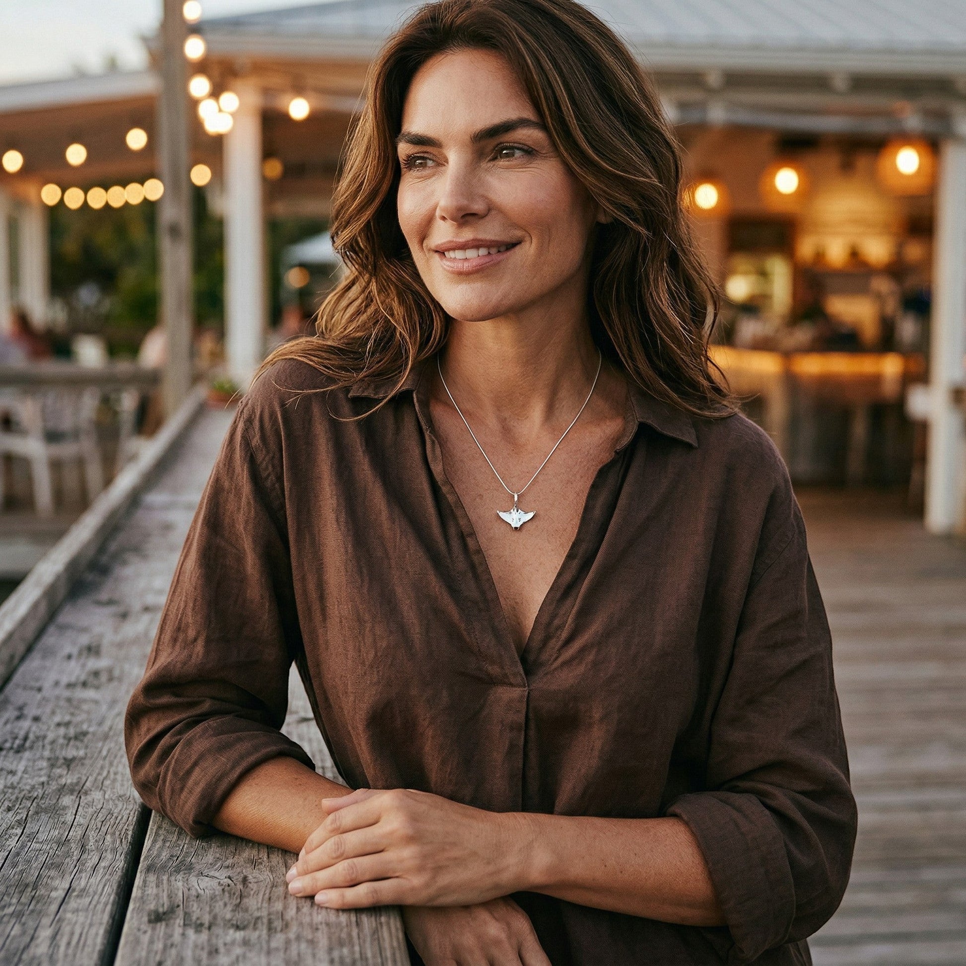 Big Blue by Roland St John sterling silver manta ray necklace on a woman wearing a brown shirt.
