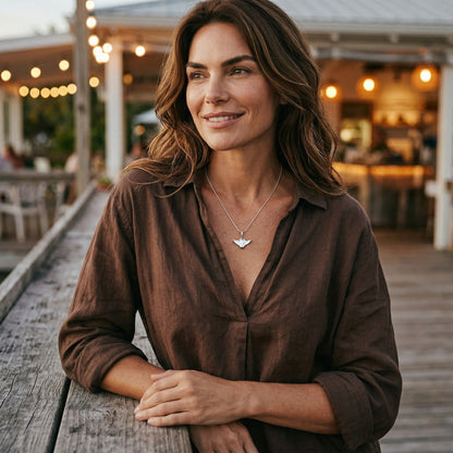 Big Blue by Roland St John sterling silver manta ray necklace on a woman wearing a brown shirt.